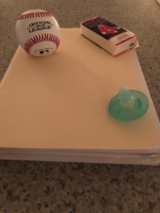A white table with a small rolled-up cloth and a green round soap.